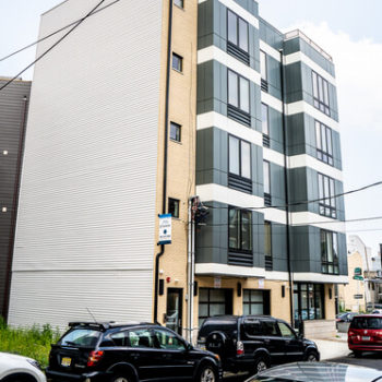 An apartment building with cars parked in front of it.