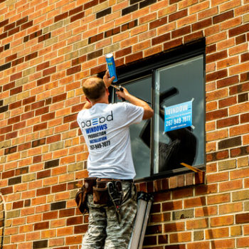 A man on a ladder working on a window.