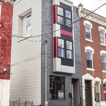 A red and black building with a car parked in front of it.