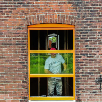 A man standing in the window of a brick building.