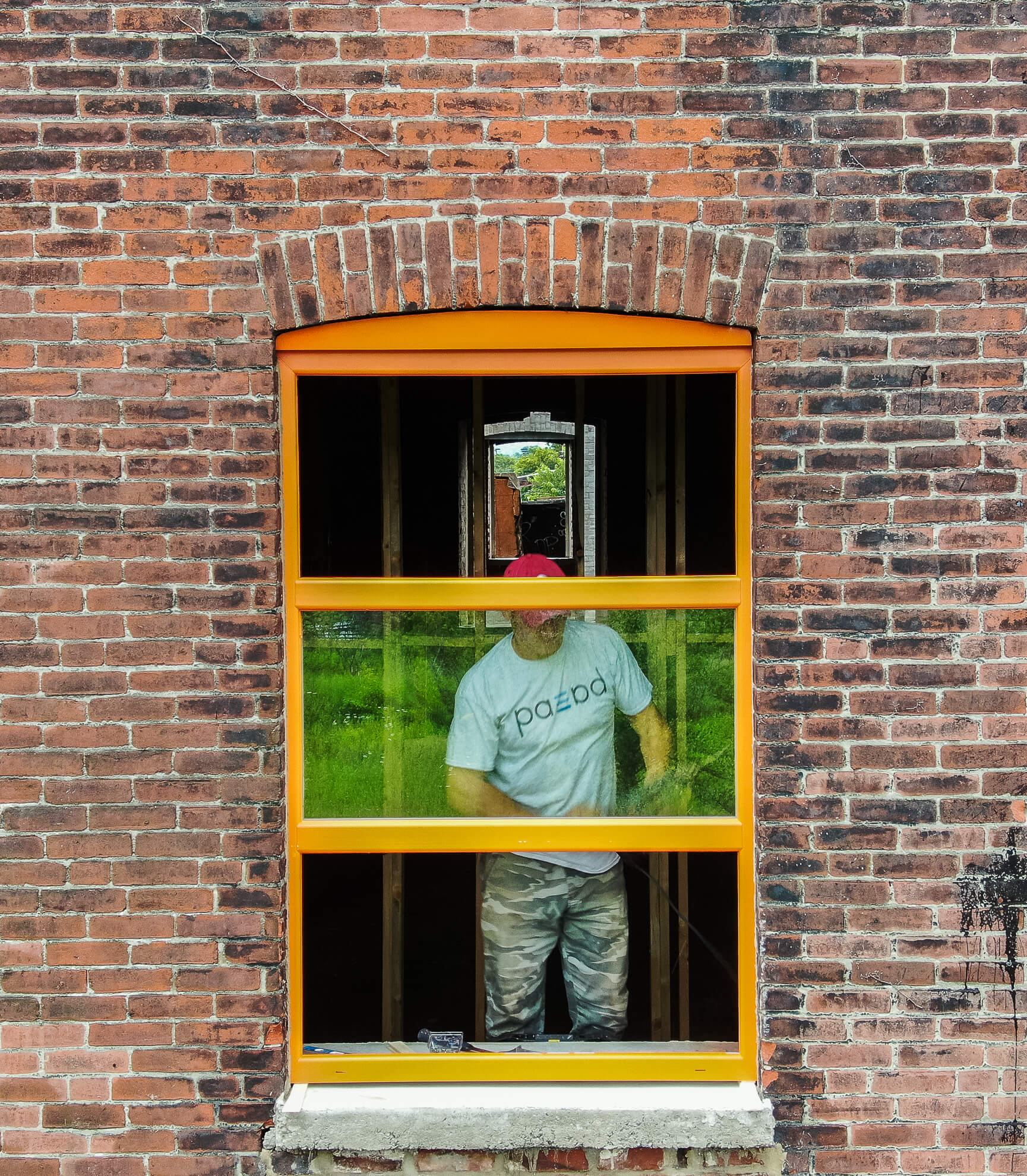 A man standing in the window of a brick building.