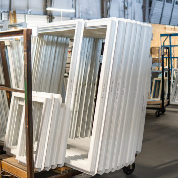 White window frames on a cart in a warehouse.