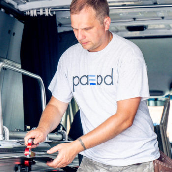 A man in a blue shirt is working on a van.