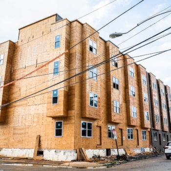 A building under construction with cars parked on the side.