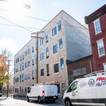 A white van is parked in front of an apartment building.