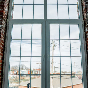 A window in a brick building with a view of a city.