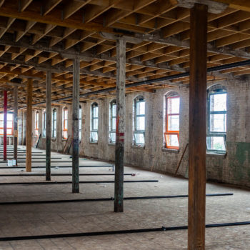 An empty room with wooden beams and windows.