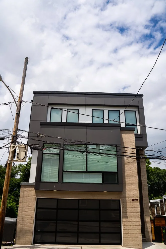 Modern three-story building with large uPVC windows and a brick exterior, showcasing time-tested durability. Power lines are visible in the foreground against a partly cloudy sky.